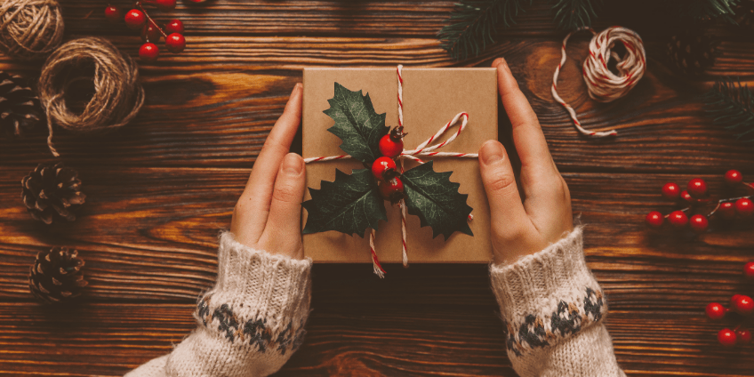 Hands holding brown paper wrapped gift for holidays
